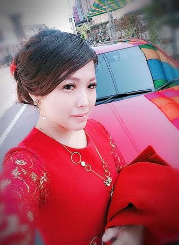 這張「一位年輕女子穿著紅色的蕾絲洋裝，站在一輛紅色跑車旁」的照片是。