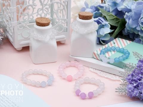 這張「手鐲和瓶子」的照片是三條不同顏色的手鐲，旁邊有兩個裝飾用的白色瓶子。