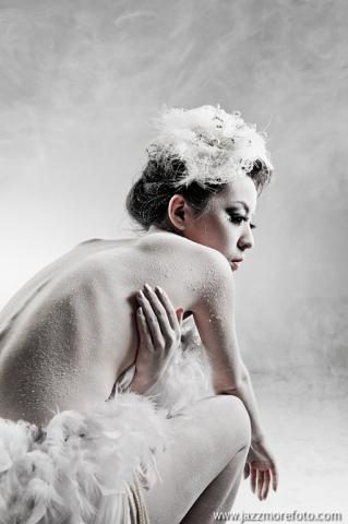 這張「一位穿著白色羽毛裝的女子，坐在椅子上，凝視著鏡頭」的照片是。