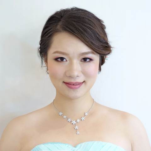 這張照片是一個穿著淡藍色禮服的女子，她戴著一條精緻的銀色花形項鍊。