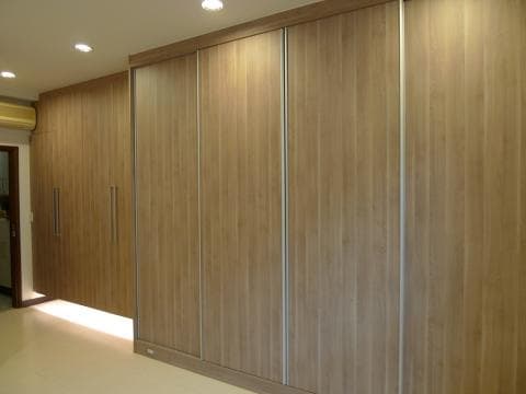 這張照片是四扇木門的衣櫃。門板是淺棕色木紋，門把手是銀色，門縫之間有銀色的邊條。整個衣櫃看起來簡潔大方。