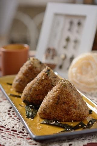 這張「飯糰」的照片是三顆金黃色的飯糰，放在黃色盤子上面，旁邊還有一些海苔。