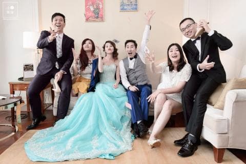 這張照片是婚禮的合照，照片中最重要的是新郎新娘，他們站在照片的中央，新娘穿著一件漂亮的婚紗，新郎則穿著西裝，他們都露出幸福的笑容。