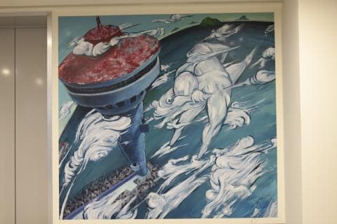 這張照片是一幅畫，畫中有一座紅色和藍色的建築，像一座塔，周圍有許多雲狀的白色形狀。建築物看起來很現代化，也許是一座摩天大樓。建築物的底部還有一群人，看起來像是正在向上望著塔。整幅畫的背景是藍色，代表天空，襯托出建築物和雲朵的顏色。