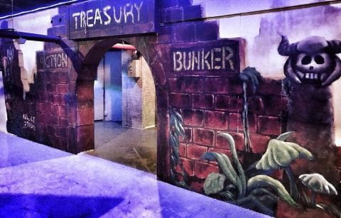 這張照片是一面塗鴉牆，上面畫著兩個拱門，一個寫著「TREASURY」，另一個寫著「BUNKER」。牆上還畫著一個戴著角的骷髏頭，看起來很嚇人。