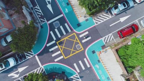 這張照片是一個十字路口，路口中央有一個用黃色線條標記的區域，看起來像是行人穿越道，但沒有行人。