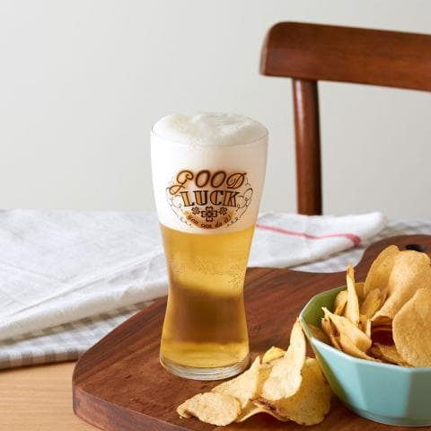 這張「啤酒杯和薯片」的照片是一杯印有「GOOD LUCK」的啤酒，旁邊放著一碗薯片。