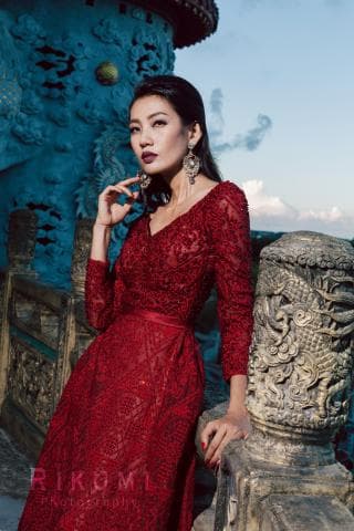 這張「一位穿著紅色蕾絲長裙的女子站在古色古香的建築旁」的照片是。