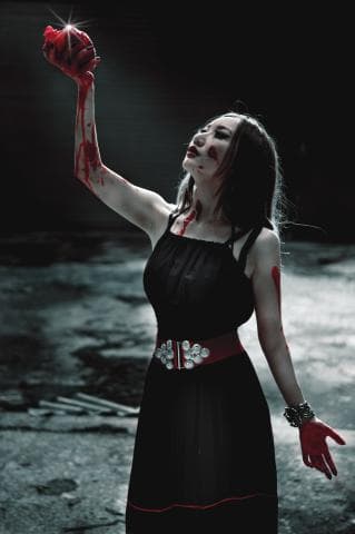 這張照片是一個女人拿著一顆血淋淋的心臟，她的表情看起來很痛苦。