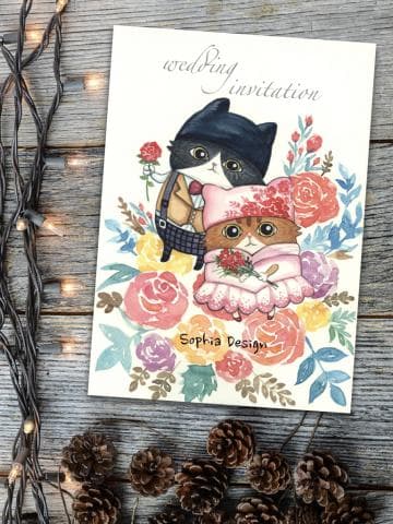 這張照片是一張婚禮邀請卡，卡片上畫著兩隻穿著禮服的貓咪，一隻是黑貓，一隻是白貓，牠們手裡都拿著花，背景是粉紅色的花朵，整體畫面非常可愛。