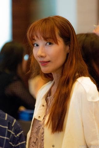 這張「漂亮女生」的照片是一個年輕女孩，她有著一頭紅色的長髮，穿著一件白色的外套，露出笑容，看起來很自信。