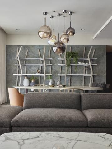 這張「現代客廳」的照片是一張灰色沙發，沙發前有一個白色大理石茶几，沙發後有一組白色開放式層架，上面擺放著一些裝飾品，牆壁上裝飾著許多球狀燈飾。