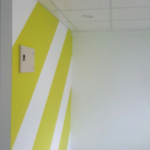 這張照片是一堵牆，牆上塗了黃色和白色的斜線，看起來很明亮。