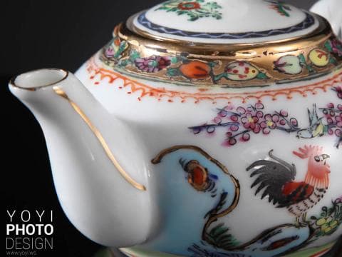 這張「茶壺」的照片是一個白瓷茶壺，上面有金色邊緣和精緻的花卉圖案，還有一個紅色公雞的圖案。