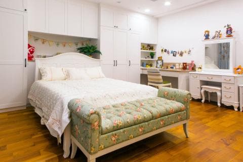 這張照片是一間臥室，最重要的是床。床上鋪著白色床單，上面放著兩個枕頭，床尾還有一個帶有花紋的腳凳。