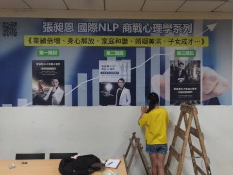 這張照片是一個現代化的空間，牆上貼著三張海報，主題是「深度國際 NLP 商戰心理學系列」。