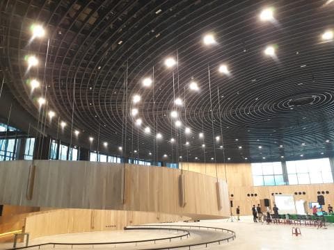 這張照片是具有獨特圓形天花板設計的現代建築。天花板採用多層圓形網格，並配有懸掛式燈光，為空間增添現代感和藝術氛圍。 
