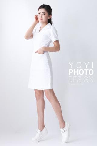 這張「一位年輕女性穿著白色制服站在白色背景前」的照片是。她穿著白色制服，手放在腰上，腳穿著白色鞋子。