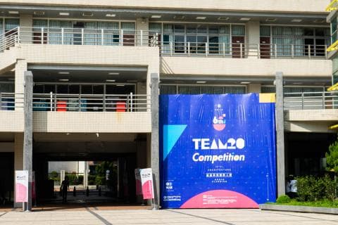 這張「TEAM20 Competition」的照片是一棟建築物的外觀，牆上掛著比賽的宣傳海報。