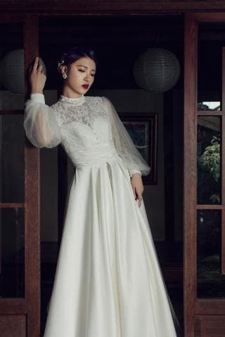 這張照片是一位身穿白色婚紗的女性。她穿著蕾絲上衣，裙襬寬大，散發出優雅與浪漫的氣息。
