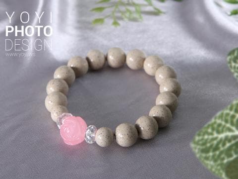 這張照片是一條由白色珠子串成的項鍊，中間有一朵粉紅色的花。