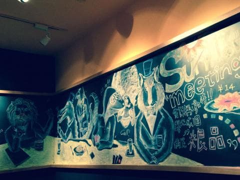 這張照片是一面牆上繪製的壁畫，壁畫上以粉筆畫著一群動物，其中一隻動物戴著帽子，並寫著“Summer Meeting”的字樣。