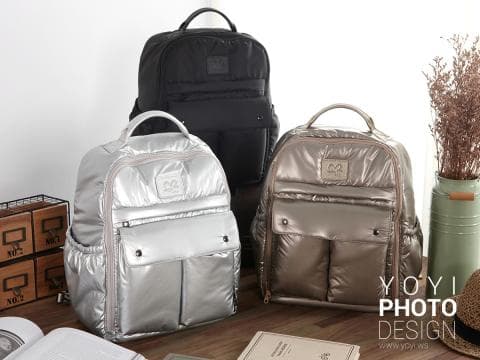 這張照片是三個揹包，其中最顯眼的是中間那個銀色揹包，它有立體的設計，讓它看起來很有質感，而且表面很光滑，讓它看起來很亮眼。