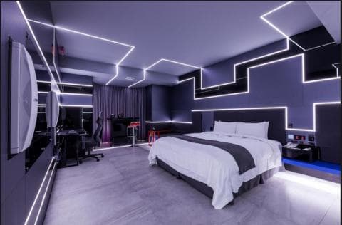 這張照片是一間現代化的酒店房間，房間裡最重要的是一張大床，床單是白色的，床頭板是黑色的，床頭兩邊還有床頭櫃。