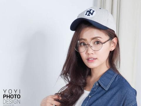 這張照片是一個戴著帽子和圓框眼鏡的年輕女孩。