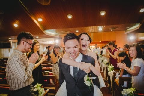 這張照片是一對新人互相依偎在一起，新郎親吻新娘的臉頰，新娘幸福地依偎在新郎懷裡，背景是婚禮現場。