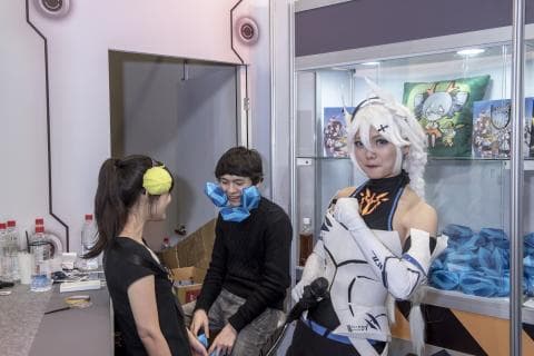 這張「Cosplay」的照片是兩位年輕人，一位女生Cos成一位遊戲角色，穿著白色衣服，戴著白色假髮，另一位男生Cos成另一位角色，穿著黑色外套和牛仔褲。