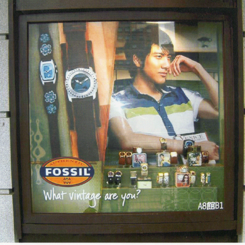 這張照片是一則 Fossil 手錶的廣告，廣告中有一位年輕男子戴著 Fossil 手錶，旁邊還有其他款式的手錶，以及「What vintage are you?」的標語。