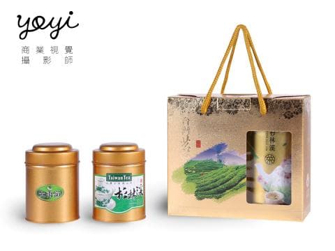 這張照片是一個金色的禮盒，裡面裝著兩罐茶葉，禮盒上有提把，方便攜帶。
