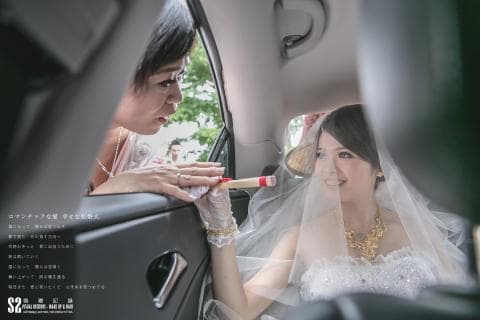 這張照片是婚禮當天新娘在車裡，準備出發前往婚禮現場的畫面。新娘穿著白色的婚紗，頭戴白紗，神情喜悅，讓人感受到她即將邁入人生新階段的幸福和期待。