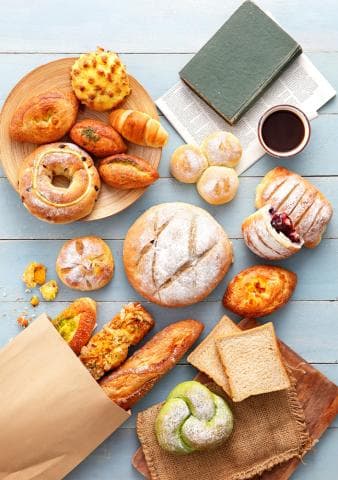 這張「麵包」的照片是各種不同形狀和種類的麵包，放在木板和紙袋上。
