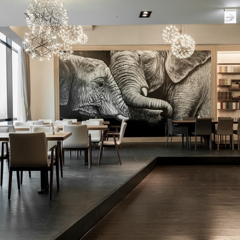 這張「現代室內設計」的照片是兩隻大象的壁畫，餐廳有一組現代的黑色桌子和椅子。