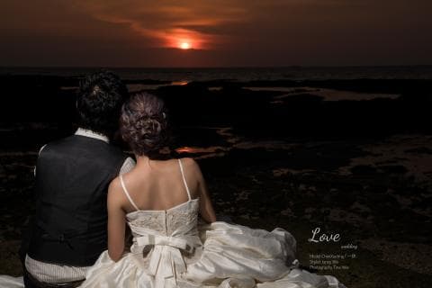 這張「婚禮」的照片是 一對新人坐在海邊，背景是夕陽。