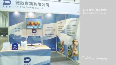 這張「展覽攤位」的照片是「岱敘科貿易有限公司」的展覽攤位，攤位上有一個大電視，上面展示著公司產品，旁邊有產品介紹的文字。攤位的背景是藍色，上面印有公司的 logo 和標語。