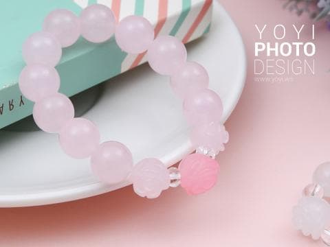 這張照片是一個粉紅色的手鍊，上面有許多小巧的粉紅色珠子，還有一個小巧的粉紅色花朵。