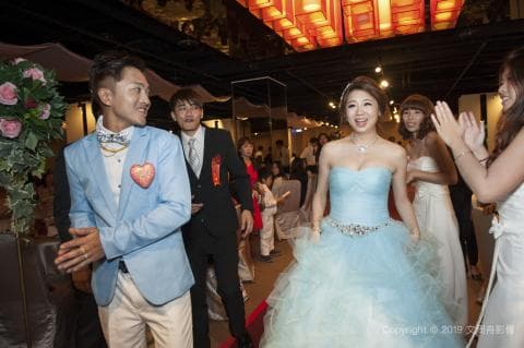 這張照片是一個婚禮現場，新娘穿著藍色的婚紗，看起來非常美麗，她正在和親朋好友們合影留念。