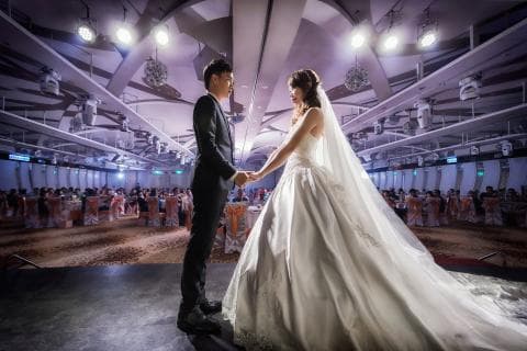 這張婚禮的照片是一對新人正在交換戒指，背景是佈置華麗的宴會廳。