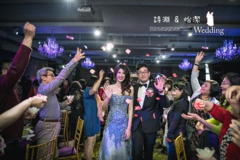 這張照片是一場婚禮，新郎新娘站在中間，他們周圍是他們的親朋好友，大家都在歡笑和祝福。