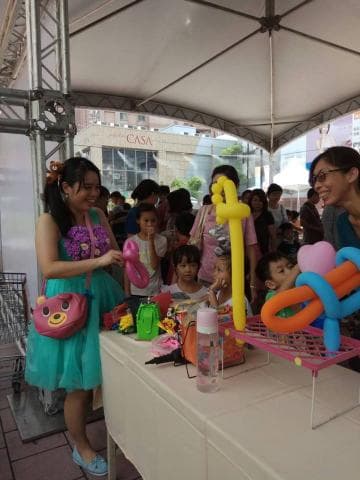 這張「遊樂場」的照片是一個年輕女性和一群兒童在玩氣球。