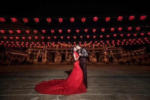 這張照片是一對新人站在紅色燈籠下，他們正互相擁抱，顯得甜蜜幸福。