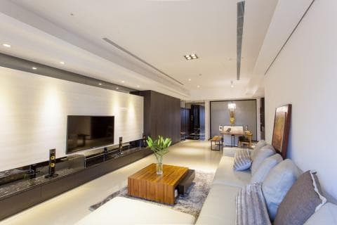 這張客廳的照片是一個現代化的空間，配備了電視、沙發和茶几，還有一個大型的落地窗，讓自然光線灑落室內，營造明亮舒適的氛圍。