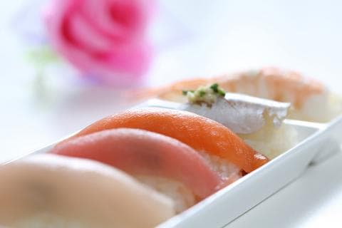 這張「壽司」的照片是幾片不同的壽司，擺放在一個白色的盤子上。