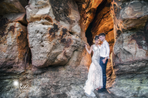 這張照片是一對新人站在岩石洞穴裡，他們相依偎，甜蜜的看著彼此。