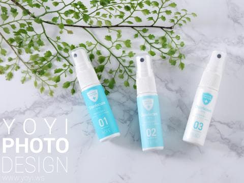 這張「消毒噴霧」的照片是三瓶不同號碼的消毒噴霧，背景是一塊白色的大理石板和綠色的植物。