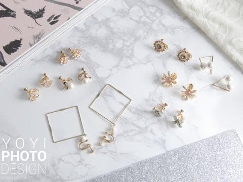 這張照片是各種不同款式的耳環，擺放在白色大理石背景上。