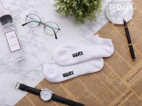 這張照片是一雙白色襪子，襪子上印有黑色的 WARX 字樣。